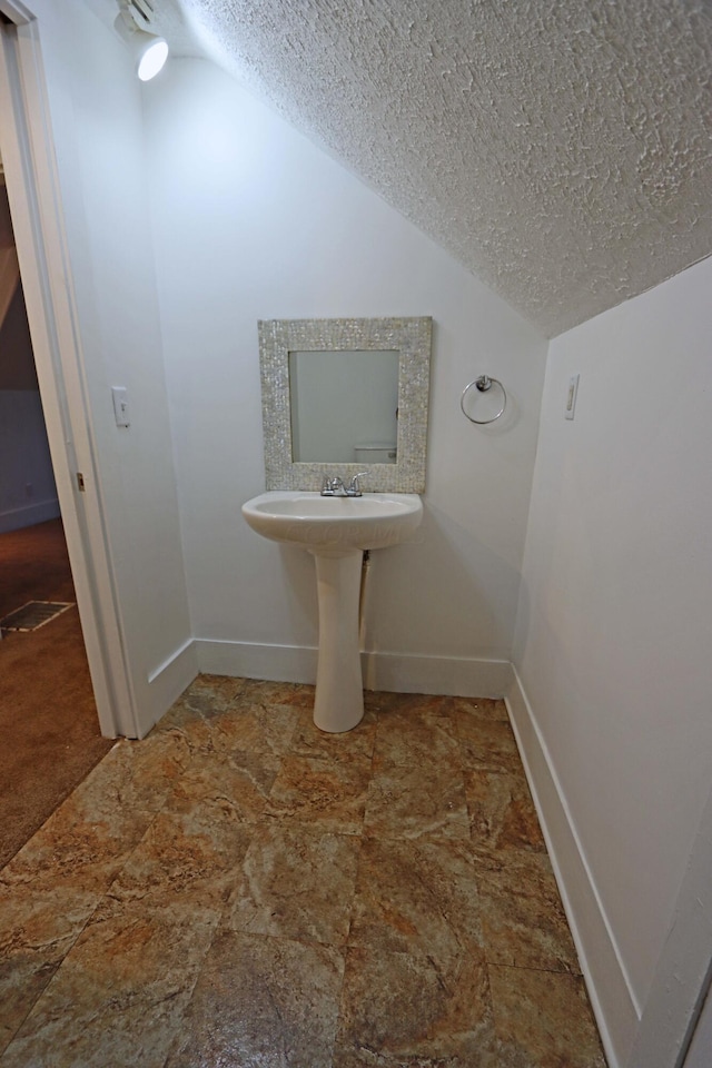 bathroom featuring a textured ceiling and lofted ceiling