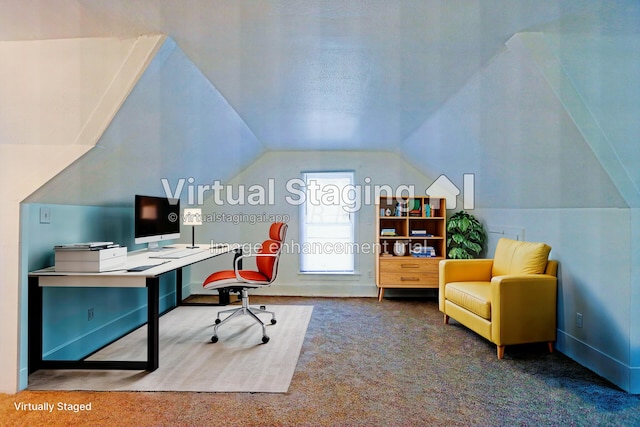 carpeted home office with built in desk and vaulted ceiling