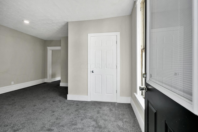 unfurnished bedroom with dark carpet and a textured ceiling