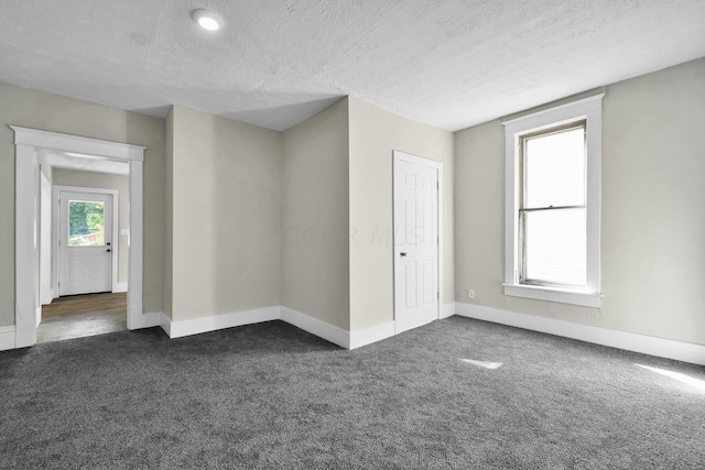 spare room with dark colored carpet and a textured ceiling