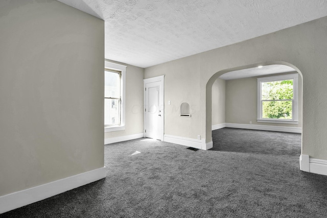 carpeted spare room featuring baseboard heating and a textured ceiling