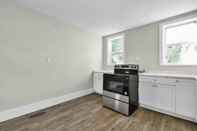 kitchen featuring white cabinets, hardwood / wood-style floors, a textured ceiling, and stainless steel range with electric cooktop