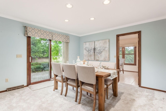 dining area with a healthy amount of sunlight, crown molding, and light carpet