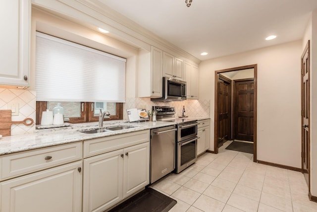 kitchen featuring appliances with stainless steel finishes, tasteful backsplash, light stone counters, sink, and light tile patterned floors