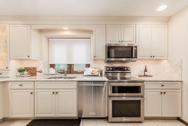 kitchen featuring sink, decorative backsplash, light stone countertops, light tile patterned floors, and stainless steel appliances