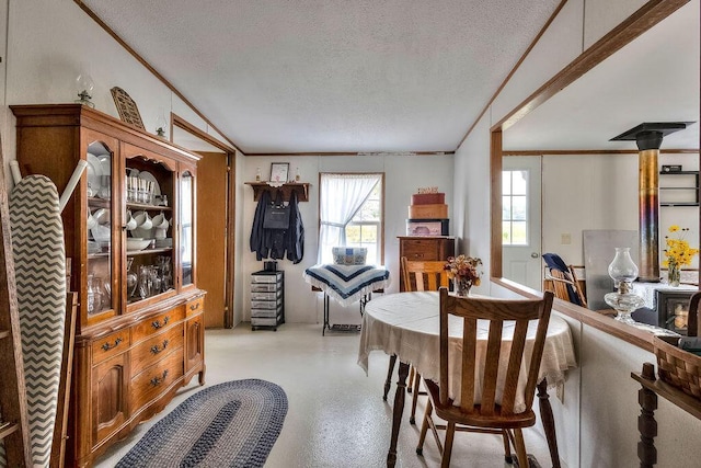 dining space with a textured ceiling, a wood stove, and crown molding