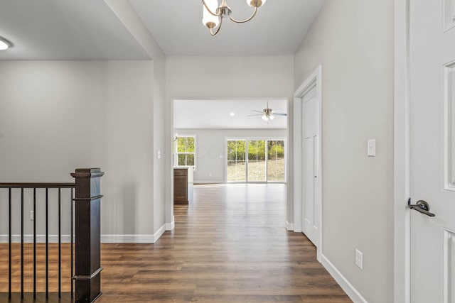 hall with dark wood-type flooring and a chandelier