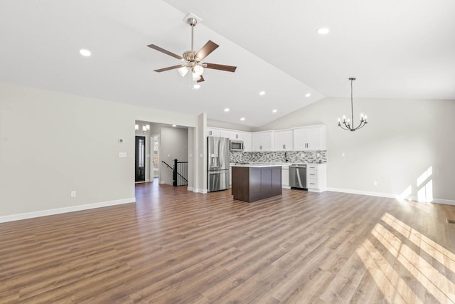 unfurnished living room featuring lofted ceiling, dark wood-type flooring, and ceiling fan with notable chandelier