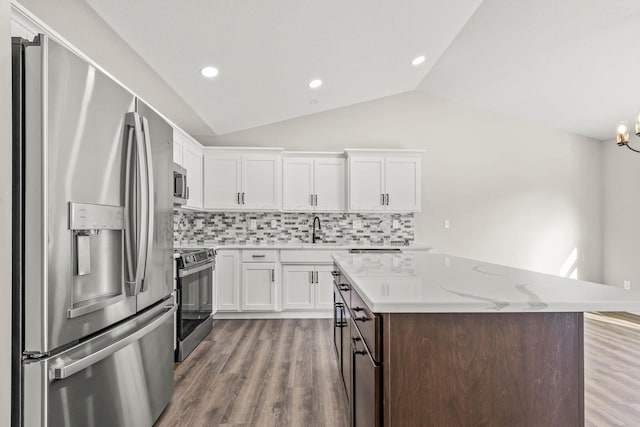 kitchen featuring lofted ceiling, sink, appliances with stainless steel finishes, a kitchen island, and white cabinets