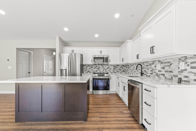 kitchen with appliances with stainless steel finishes, white cabinetry, sink, a center island, and dark wood-type flooring