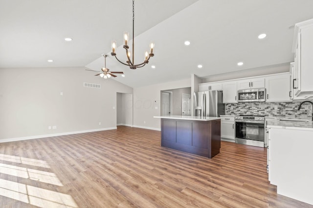 kitchen featuring a kitchen island, appliances with stainless steel finishes, sink, white cabinets, and decorative backsplash