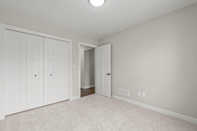 unfurnished bedroom featuring light carpet and a closet