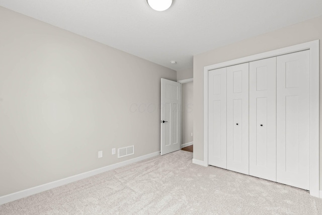 unfurnished bedroom featuring light colored carpet and a closet