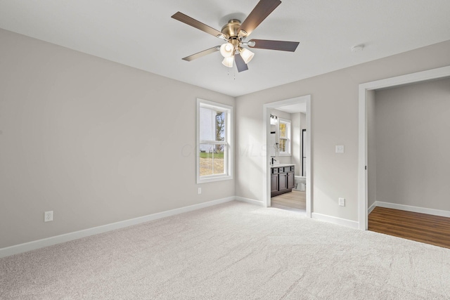 unfurnished bedroom featuring light carpet, ensuite bath, and ceiling fan