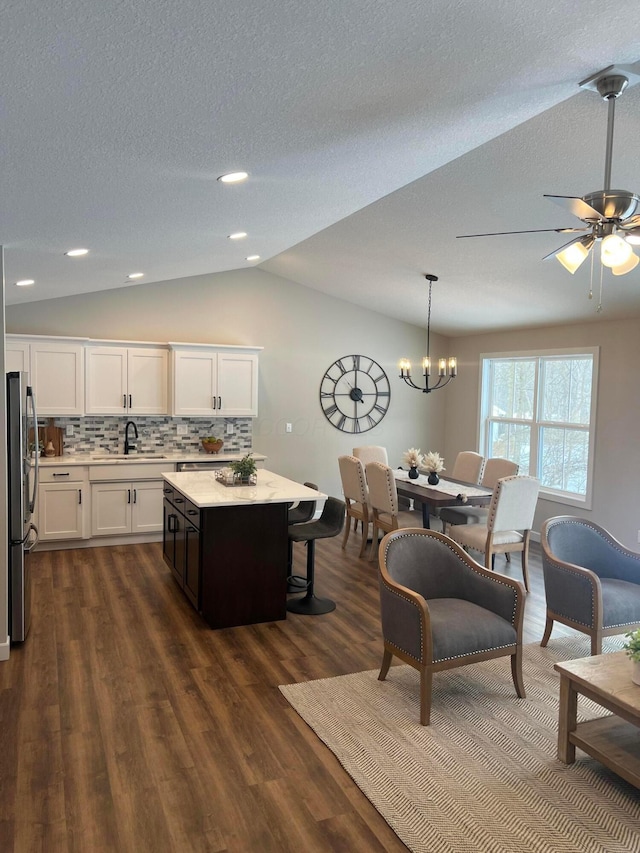 kitchen with stainless steel fridge, hanging light fixtures, a center island, white cabinets, and decorative backsplash