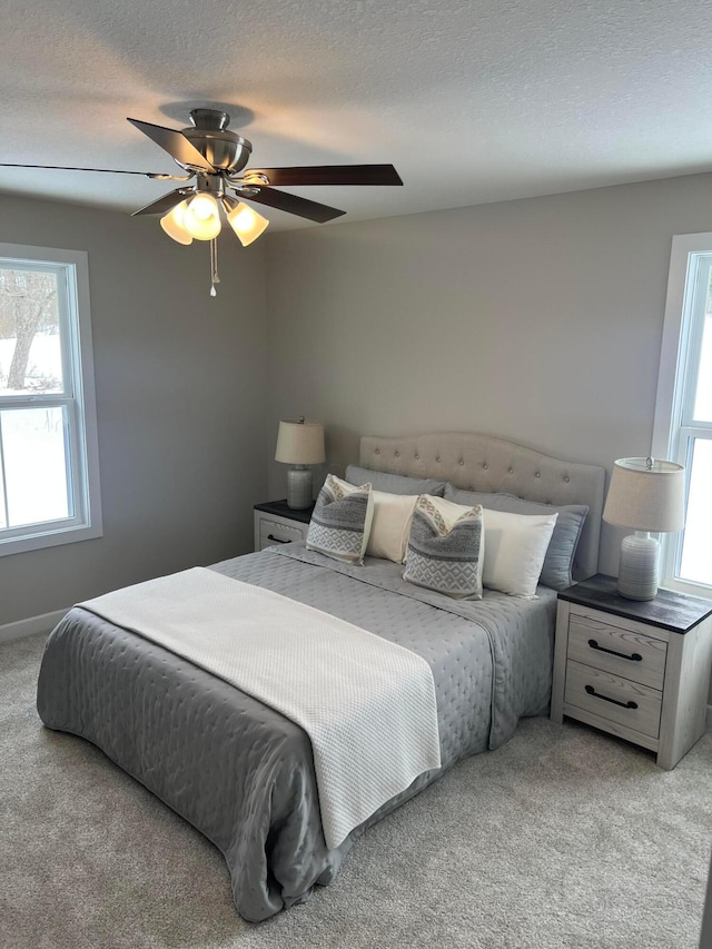 carpeted bedroom featuring ceiling fan and a textured ceiling