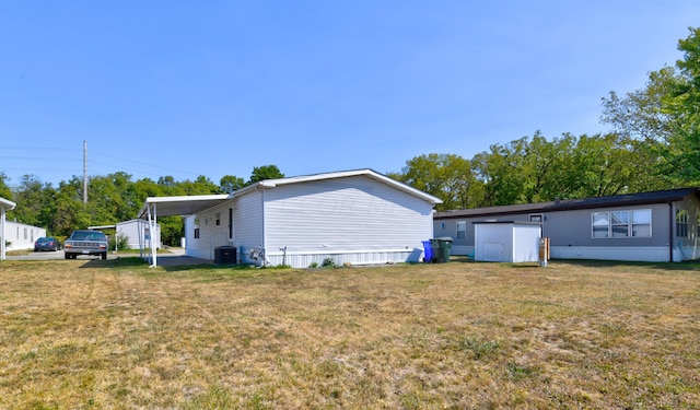 exterior space with a yard, central AC unit, a carport, and a storage shed