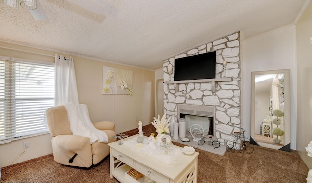 carpeted living room featuring a stone fireplace, crown molding, ceiling fan, and a textured ceiling