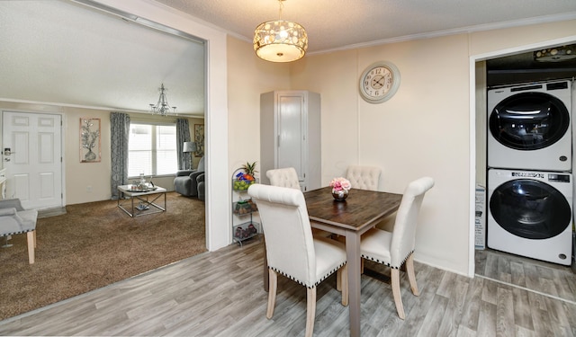 dining room with ornamental molding, a textured ceiling, stacked washing maching and dryer, and light hardwood / wood-style floors