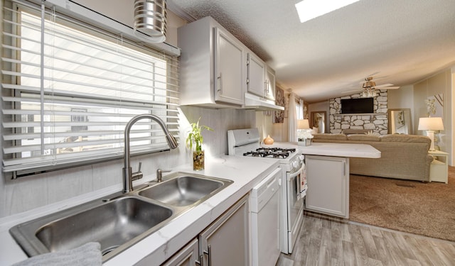 kitchen with lofted ceiling, white appliances, sink, light wood-type flooring, and white cabinetry