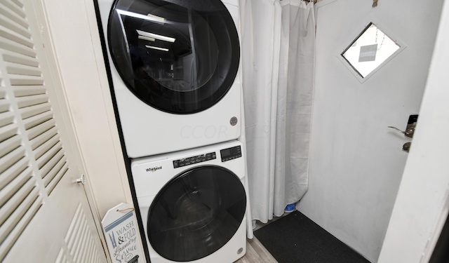 clothes washing area with light hardwood / wood-style floors and stacked washer / dryer