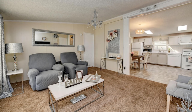 living room featuring light wood-type flooring, a textured ceiling, crown molding, sink, and a chandelier