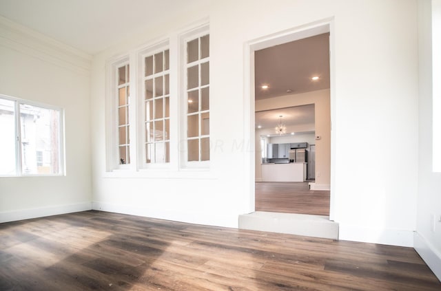 spare room featuring hardwood / wood-style floors and an inviting chandelier