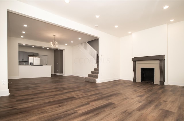 unfurnished living room with dark wood-type flooring and an inviting chandelier