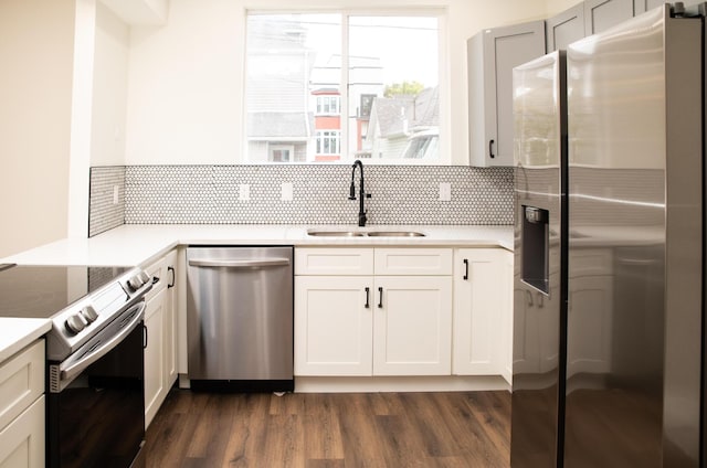 kitchen with white cabinets, sink, dark hardwood / wood-style floors, appliances with stainless steel finishes, and tasteful backsplash