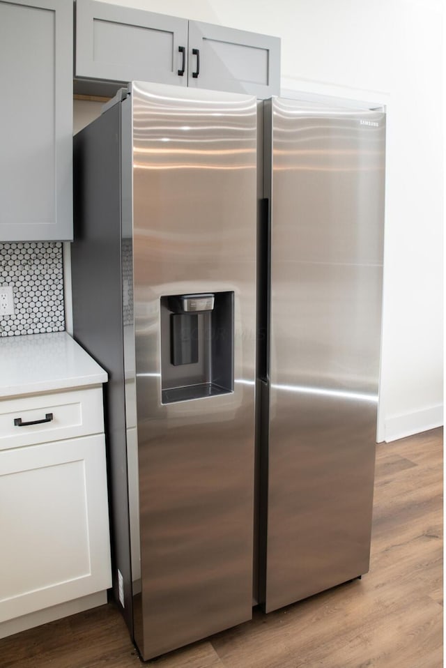 kitchen with backsplash, light hardwood / wood-style floors, and stainless steel refrigerator with ice dispenser