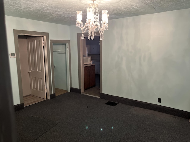 empty room featuring a textured ceiling and a notable chandelier