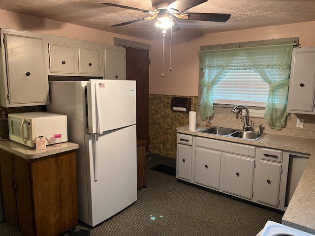 kitchen with a textured ceiling, white cabinetry, sink, and white appliances