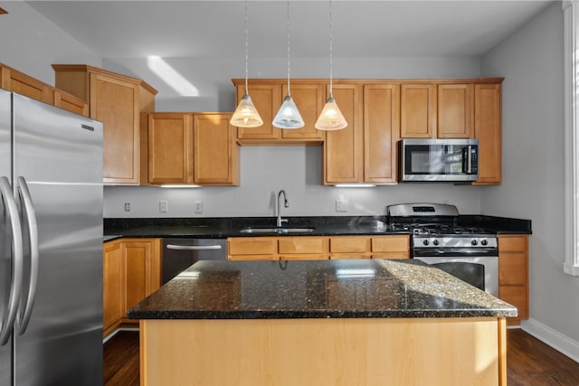 kitchen featuring appliances with stainless steel finishes, decorative light fixtures, sink, dark stone countertops, and a center island