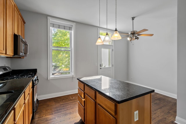 kitchen featuring dark stone counters, dark hardwood / wood-style floors, range with gas stovetop, and a center island