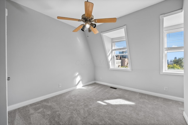 spare room with carpet floors, vaulted ceiling, ceiling fan, and a healthy amount of sunlight