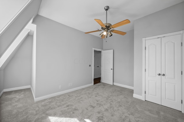 unfurnished bedroom with vaulted ceiling, ceiling fan, a closet, and light carpet