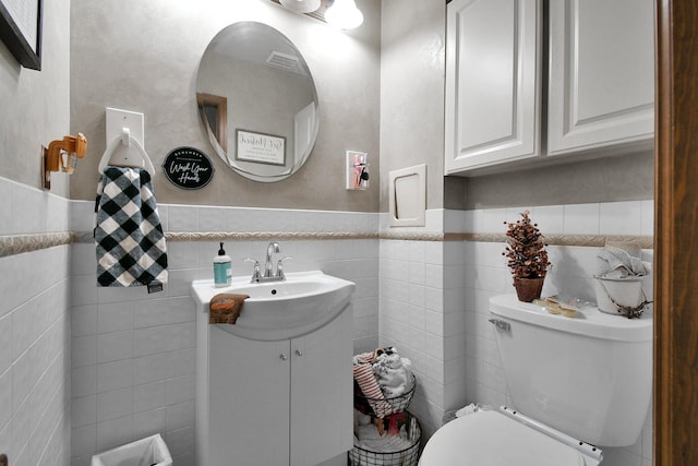 bathroom featuring vanity, tile walls, and toilet