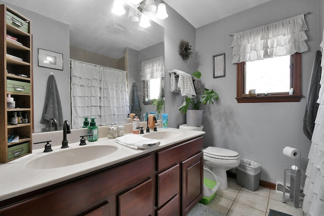 bathroom featuring tile patterned flooring, vanity, toilet, and a healthy amount of sunlight