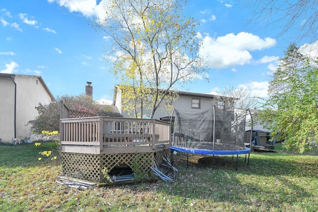 back of property featuring a trampoline, a lawn, and a wooden deck