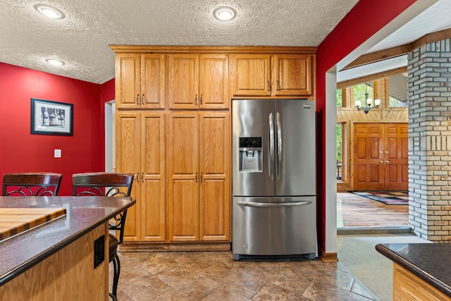 kitchen featuring stainless steel refrigerator with ice dispenser, a textured ceiling, hardwood / wood-style flooring, a notable chandelier, and lofted ceiling