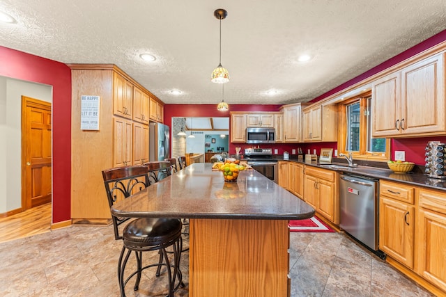 kitchen with a textured ceiling, a center island, a kitchen bar, and stainless steel appliances