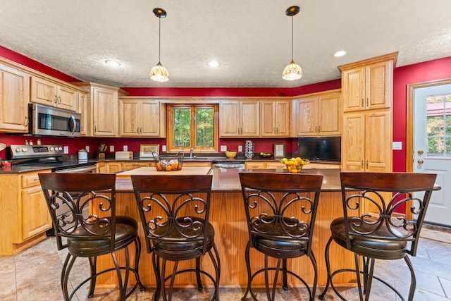 kitchen with pendant lighting, a center island, stainless steel appliances, and a textured ceiling