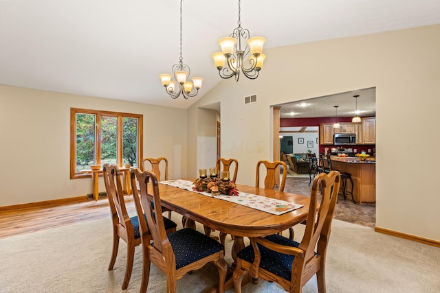 carpeted dining room featuring a chandelier and vaulted ceiling