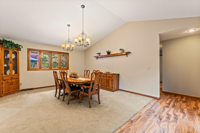 dining room featuring a notable chandelier, light hardwood / wood-style floors, and lofted ceiling