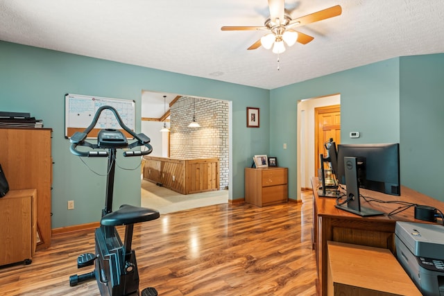 home office with a textured ceiling, light wood-type flooring, and ceiling fan