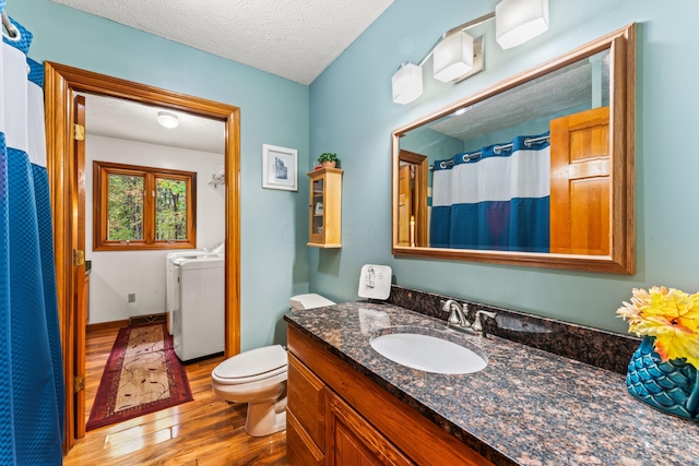 bathroom featuring hardwood / wood-style floors, vanity, toilet, independent washer and dryer, and a textured ceiling