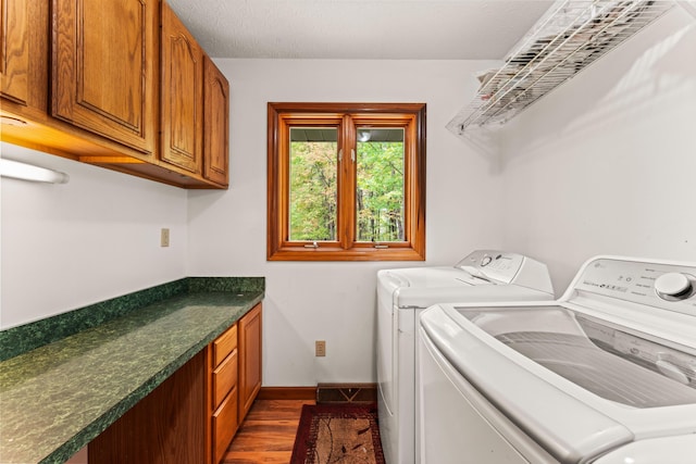 laundry area with a textured ceiling, cabinets, washer and dryer, and dark hardwood / wood-style floors