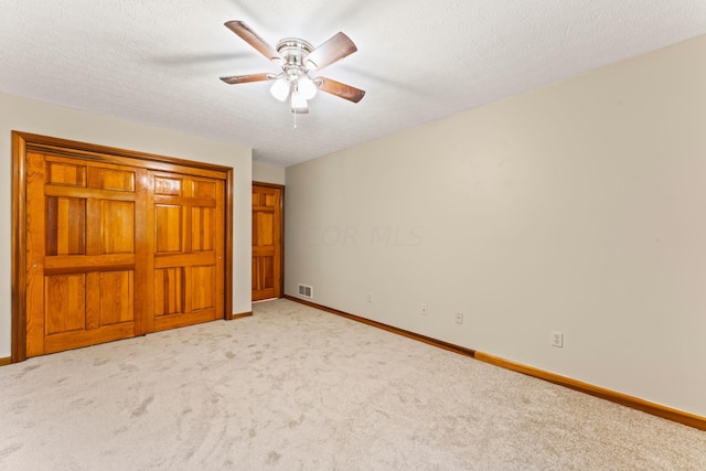 unfurnished bedroom featuring a textured ceiling, light colored carpet, and ceiling fan