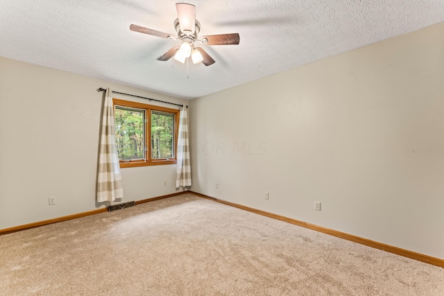 empty room with carpet flooring, ceiling fan, and a textured ceiling