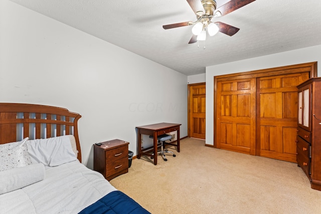 bedroom featuring ceiling fan, light colored carpet, and a textured ceiling